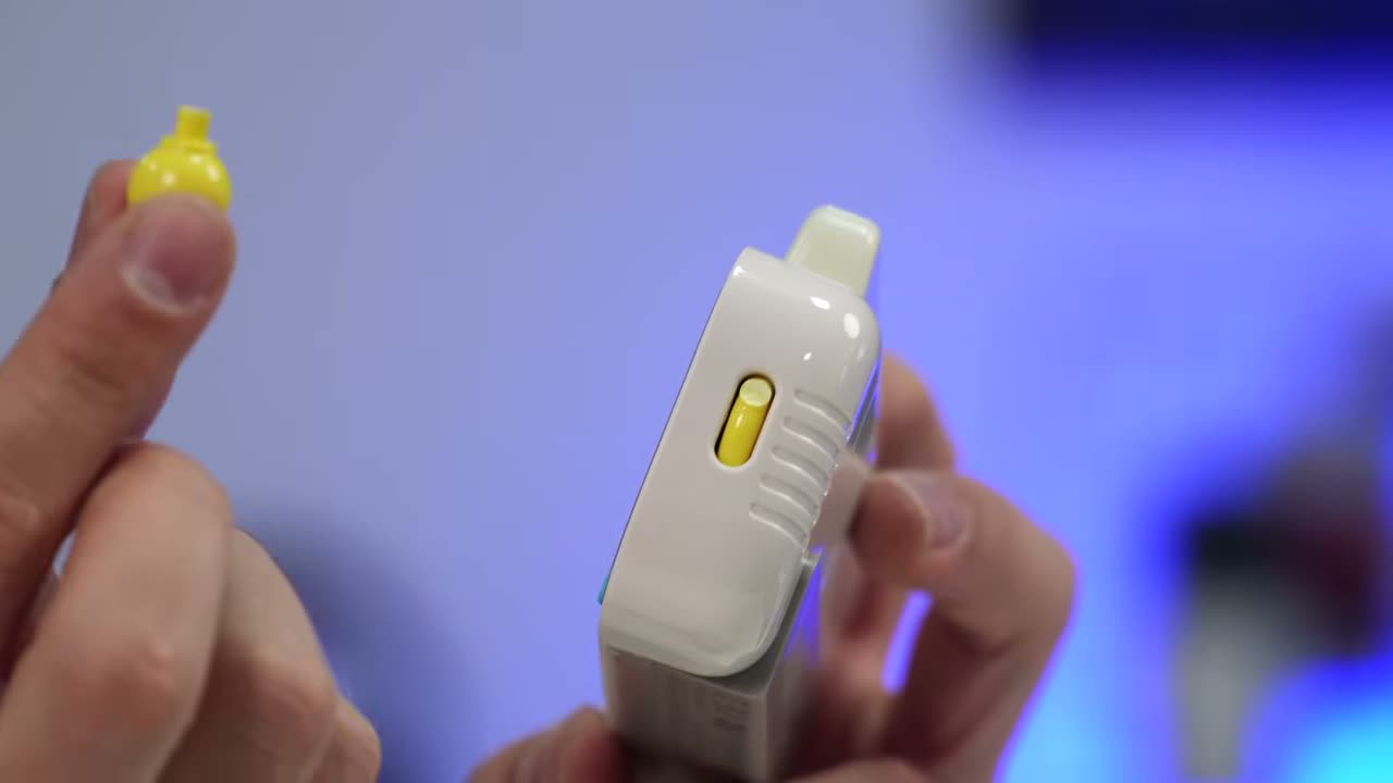 Pequeno acessório eletrônico branco com botão amarelo